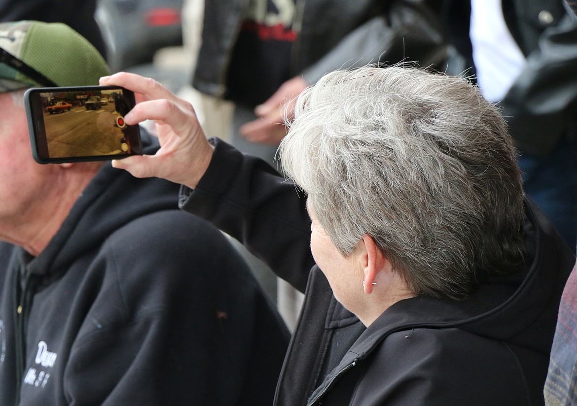 (Photo by CAROLINE LOBSINGER)A fan of classic cars captures the action on her cellphone during Friday's Lost in the '50s car parade.