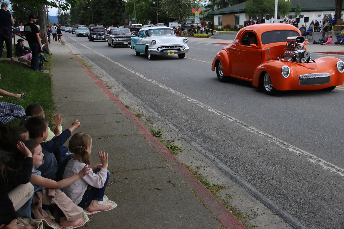 (Photo by MARY MALONE)Youngsters on Division Avenue wave as vintage cars pass by.