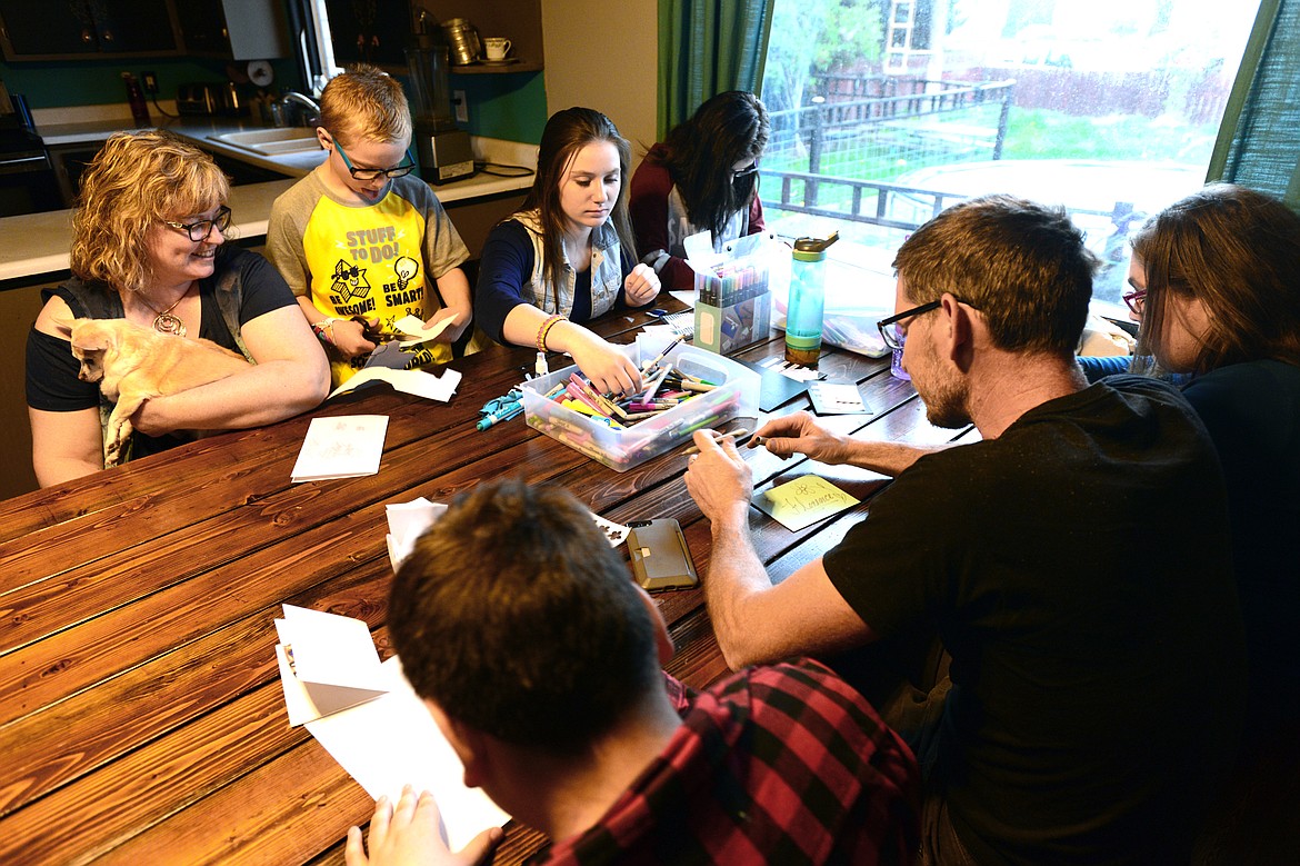 Clockwise from top left, Tamara Horton, son Gideon, daughter Jasmine, neighbor Kaylynn, daughter T.K., husband Nate and son Evan create handmade cards at their kitchen table so that Tamara could take them with her on a quick trip to visit her oldest daughter Florence,who is married and lives in Arizona. (Casey Kreider/Daily Inter Lake)