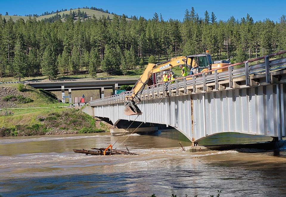 Crews remove a large tree anchored onto the Petty Creek bridge last weekend near Alberton for fear other debris would build up around it. (Photo by Jay Styles)