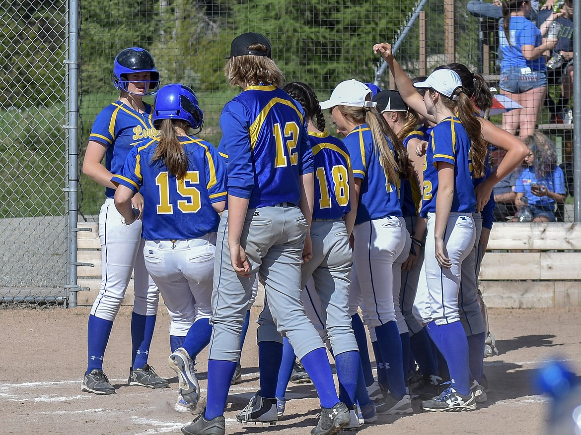 Libby sophomore Sheyla Gallagher (15) is surrounded by teammates as she scores from her home run in the third inning of the first game of the Libby-Troy double header Tuesday. (Ben Kibbey/The Western News)