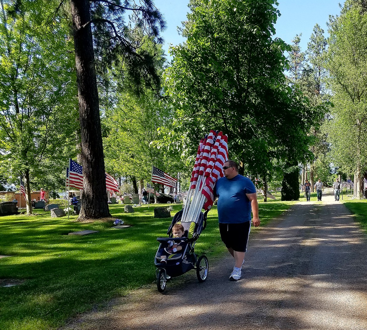 Rodney Burtis II and his young son, Schuyler, carry flags to place on veterans' graves at Evergreen Cemetery in Post Falls on Saturday. Over 600 flags were placed by volunteers in preparation for American Legion Post 143's Monday Memorial Day ceremony at 10 a.m.
(Photo by KERRI THORESON)