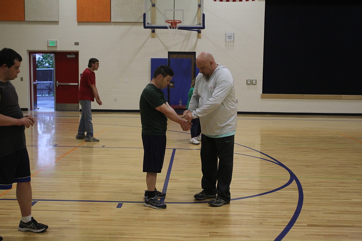 Specialized Needs Recreation dad and coach Jim Kenney shows SNR participant Mark Pennestri where on his wrist to hit a volleyball during a practice May 17 at the Winton Elementary School gym.