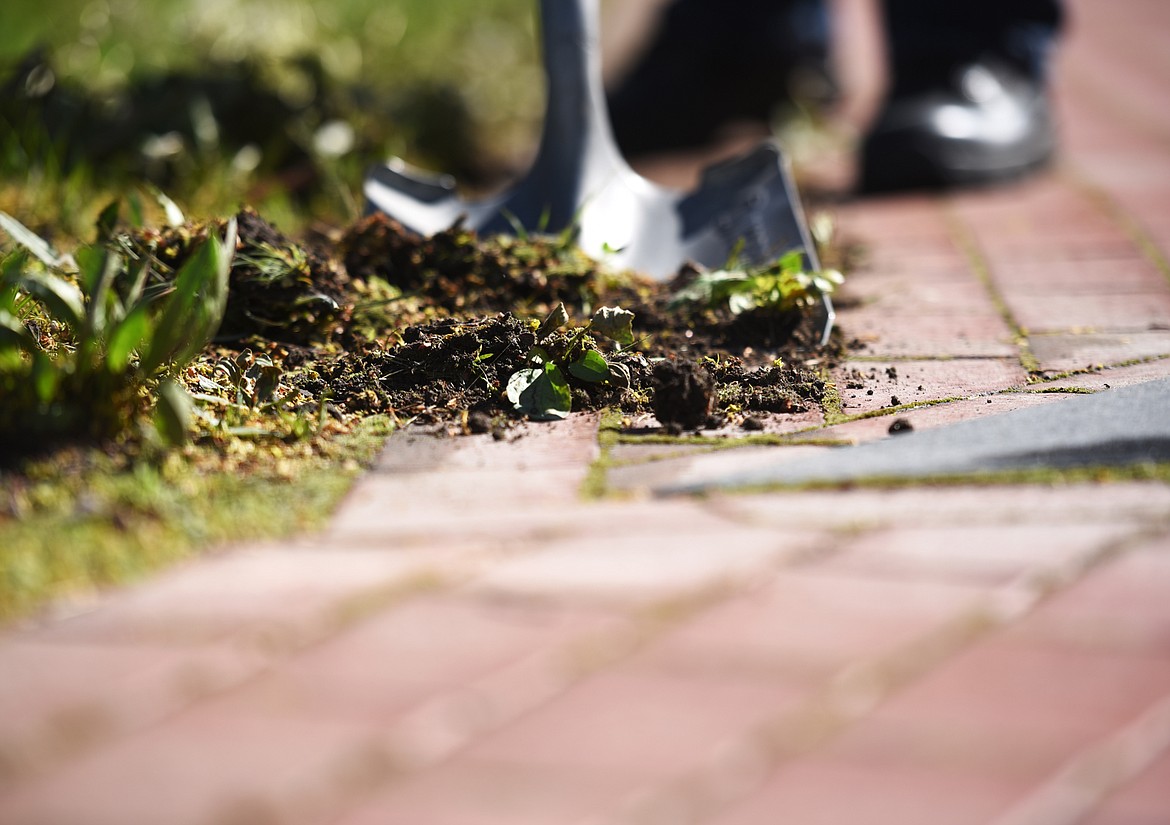 WD Dillworth uses a shovel to clear the bricks where dirt and grass have begun to encroach on the memorial bricks at the Veterans Memorial on Saturday, May 20, at Depot Park in Kalispell.(Brenda Ahearn/Daily Inter Lake)