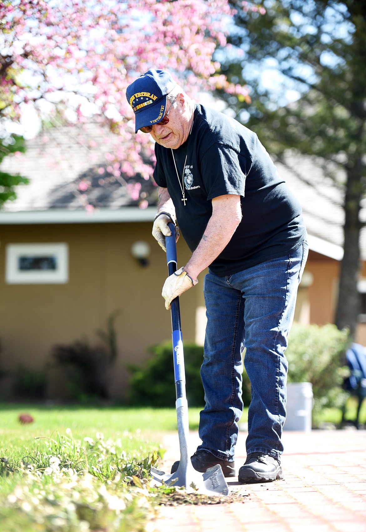 WD Dillworth uses a shovel to clear dirt and grass that has encroached on the memorial bricks at the Veterans Memorial.