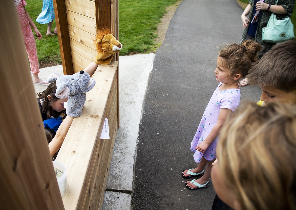 Cara LaRiviere, 5, listens and watches a play at the puppet station Wednesday afternoon at Fernan  Elementary's new Playground For All. The materials for the station were donated by Coeur d'Alene Kiwanis. Lawrence Kiefer built the booth. (LOREN BENOIT/Press)