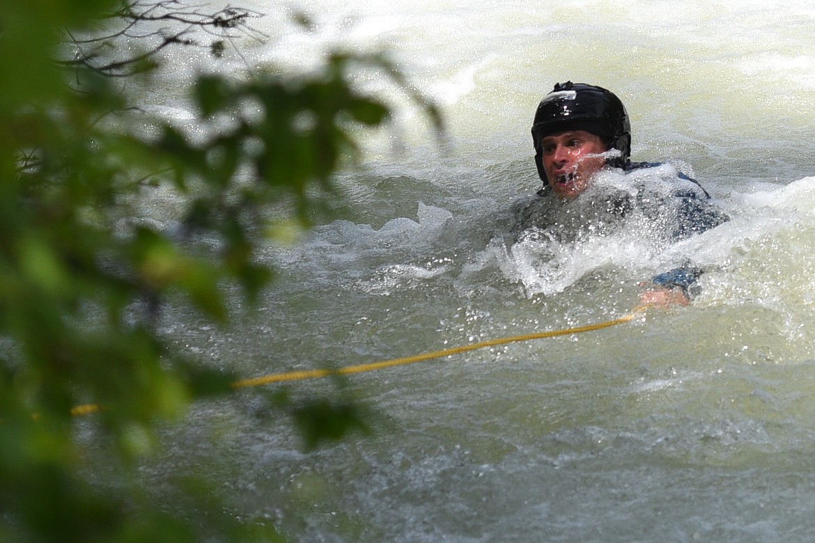 A capsized kayaker is pulled ashore in the Swan River during the Expert Slalom event at the Bigfork Whitewater Festival in Bigfork on Saturday. (Casey Kreider/Daily Inter Lake)