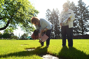 Cate Webber, left, and Pat Gillies, officers with the Chief Ignace Chapter of the National Society Daughters of the American Revolution, place an American flag at the gravestone of past member Anna Miller Yeaton in Conrad Memorial Cemetery in Kalispell on Friday morning. The organization, founded in 1890, has a mission of promoting historic preservation, education and patriotism. (Casey Kreider photos/Daily Inter Lake)