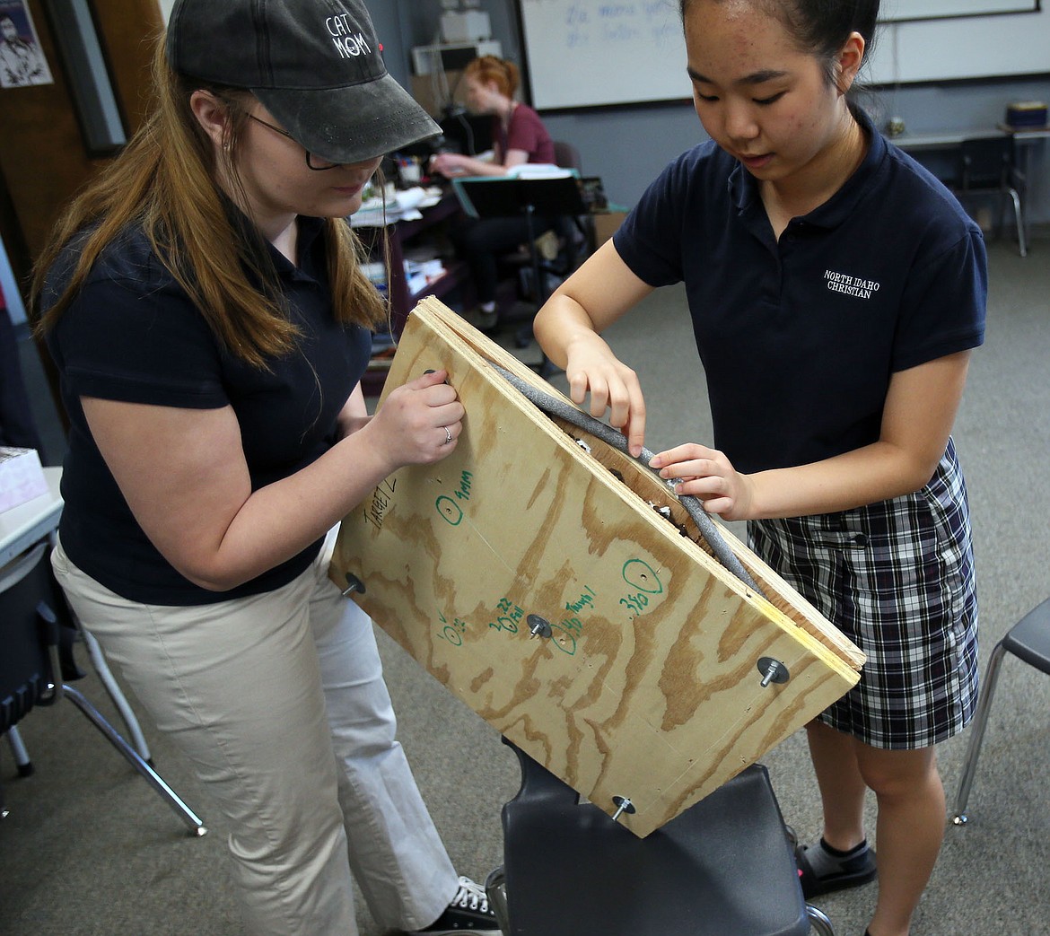 Jennika Bettis and Anna Cho show playground rubber chips, held in by foam and packed between thick plywood, used in one prototype of their bullet-resistant desk concept. (JUDD WILSON/Press)