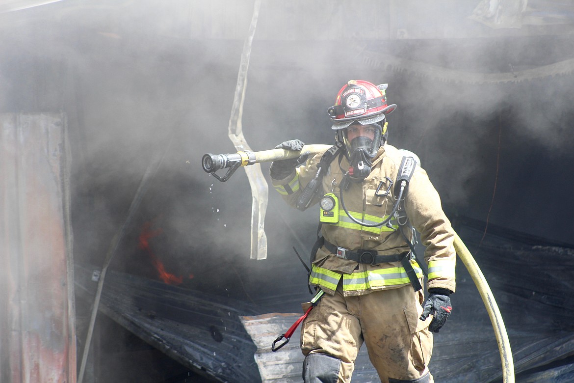 Malsom carries a hose away from the garage after spraying it down.