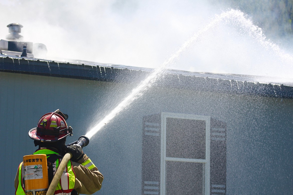 SCFD No. 1 firefighter John Miller hoses down the roof of the home to keep the flames from reaching the other side.