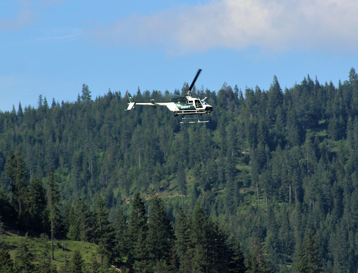 Photo by CHANSE WATSON/ A Spokane County Search and Rescue helicopter circles the area over Enaville.