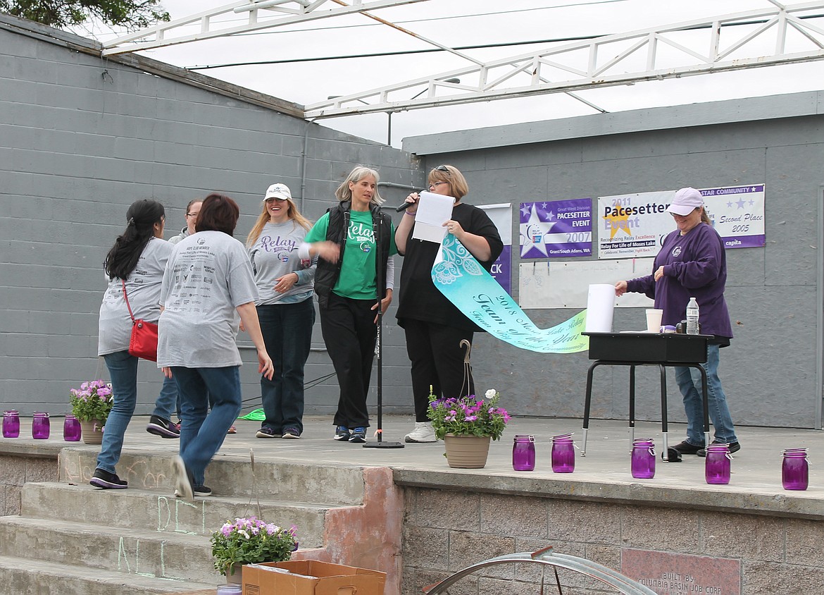 Joel Martin/Columbia Basin Herald
Charlene Rios, third from right, of Big Bend Community College, accepts the Team of the Year banner from Relay &#145;chaos coordinators&#146; Josie Sisson and Donna Anderson at the Relay for Life Friday night.