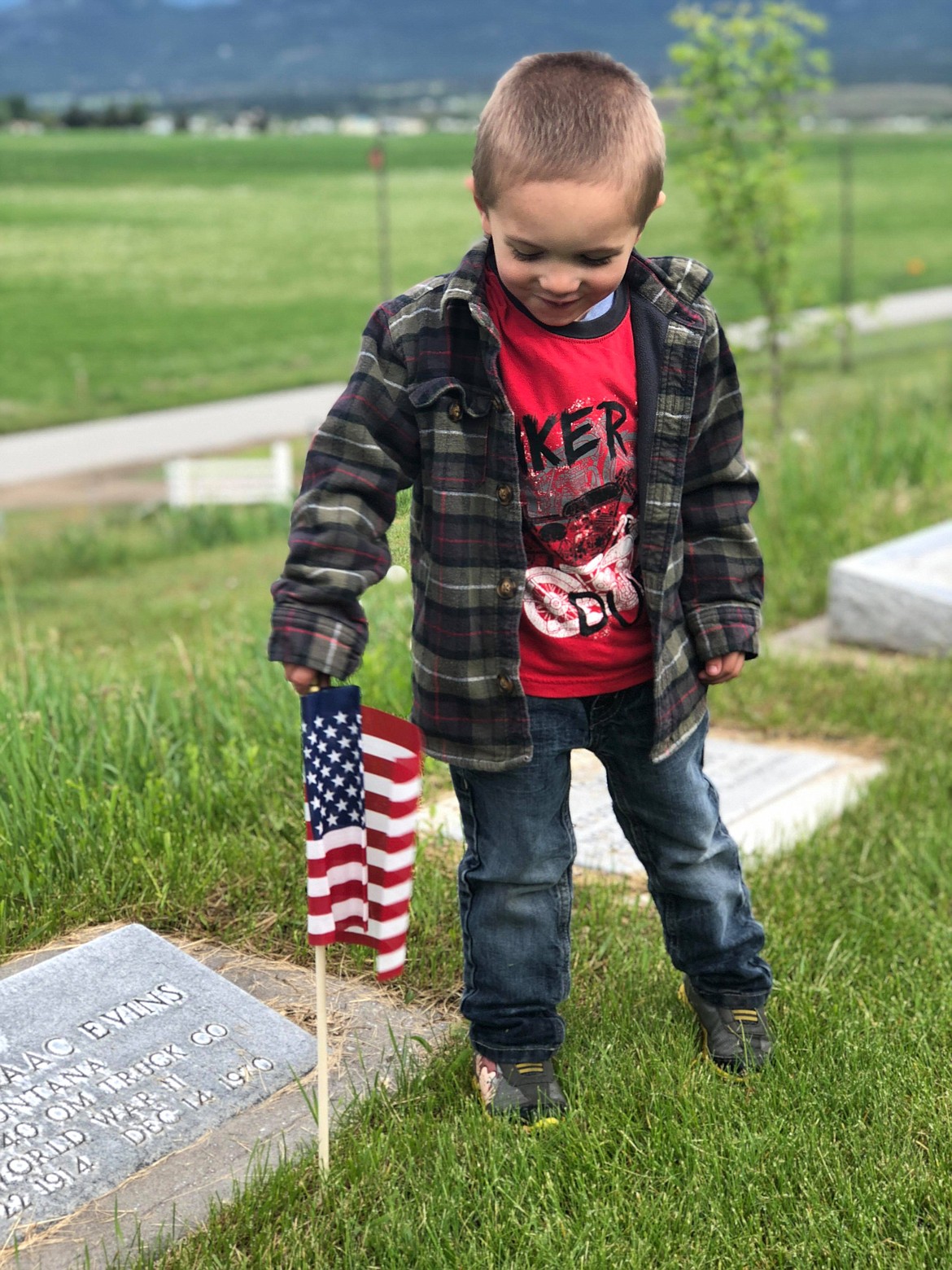 Jeramiah Goodwin helps set flags in their holders with other Plains VFW members at the local cemetery in preparation for Memorial Day. (Erin Jusseaume/ Clark Fork Valley Press)