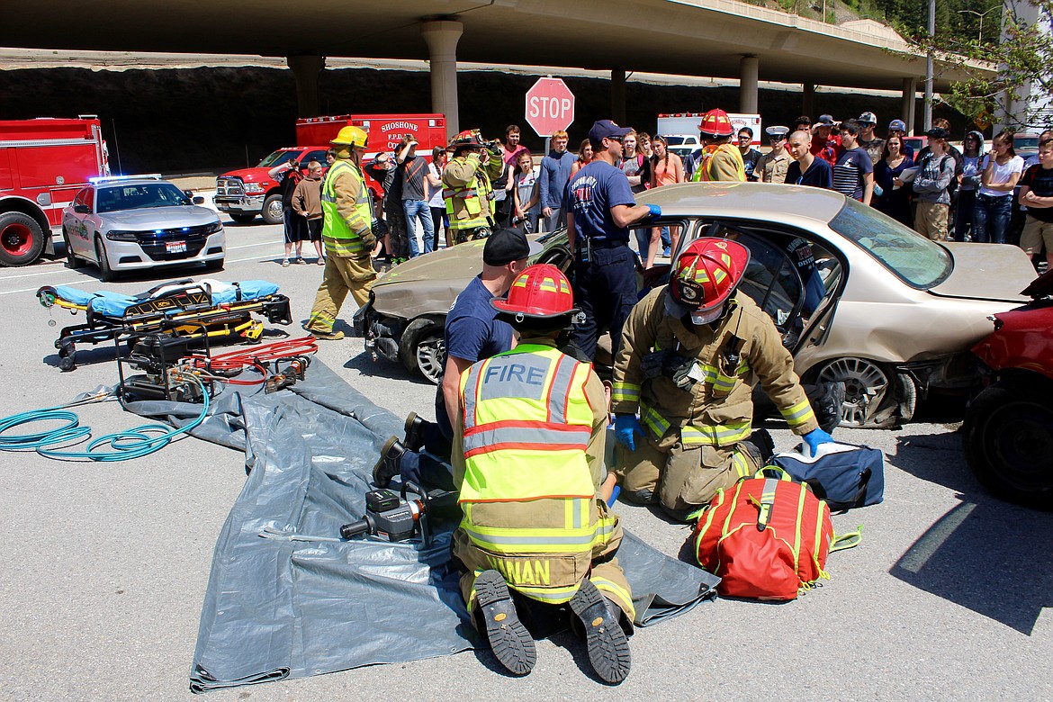 Shoshone County Fire District No. 1 crews strap Aby Berger onto a stretcher and remove others from the car as students observe.