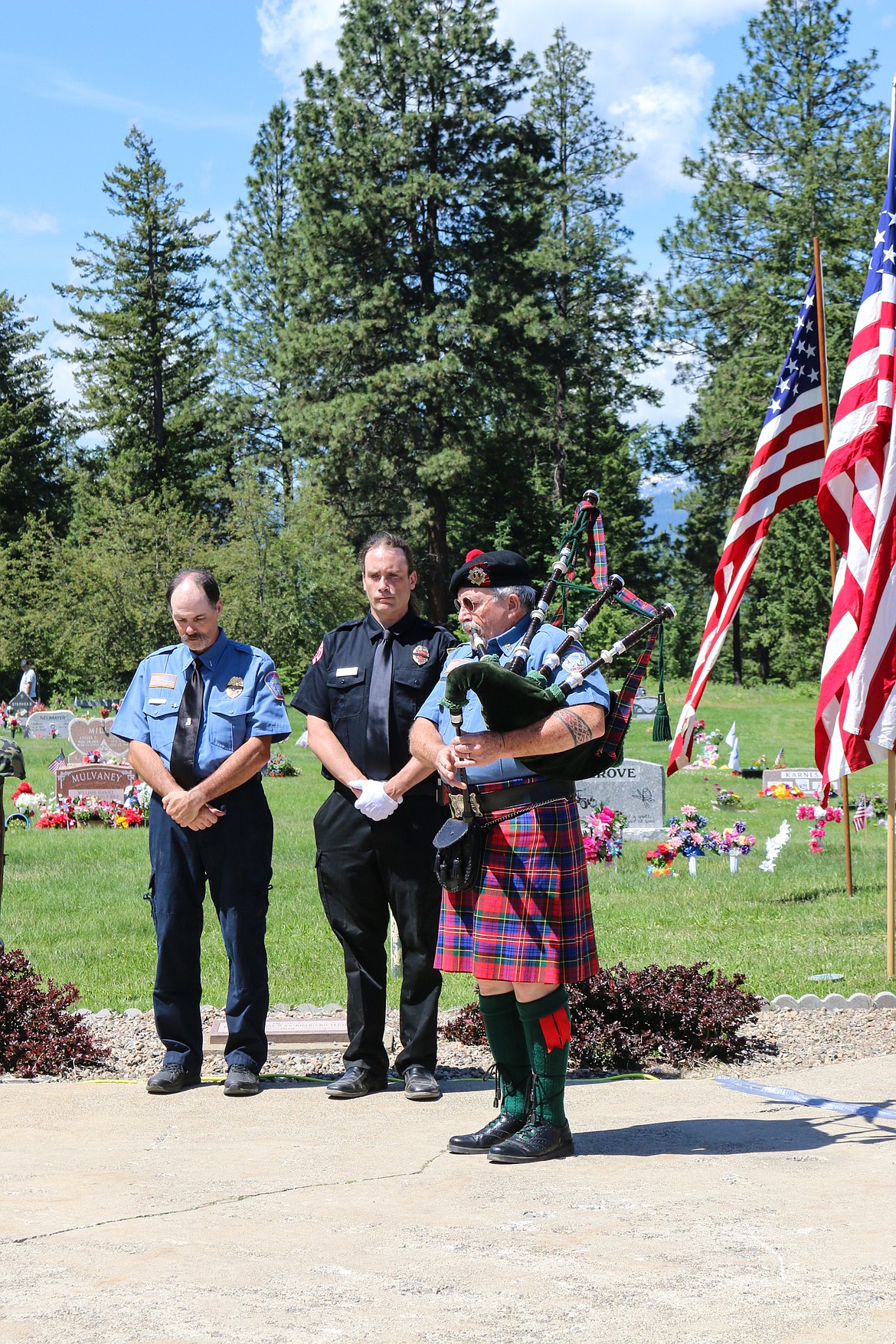 Photo by MANDI BATEMAN
Alan Hamilton and Wally Nyberg stand by as Pat Warkentin plays Amazing Grace on the bagpipes.