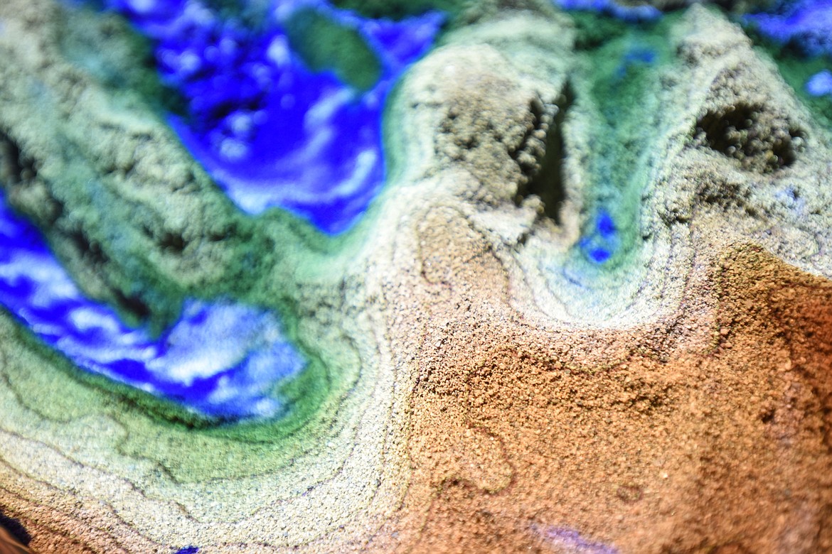 The washed playground sand shows topographical lines indicating elevation, and blue indicates water and rainfall, allowing the students to see how rainfall will move through a landscape.(Brenda Ahearn/Daily Inter Lake)