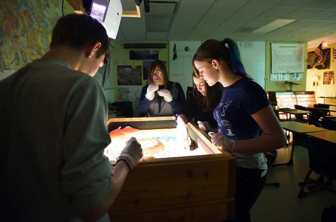 Students use an augmented reality sandbox to create a lunar landscape.