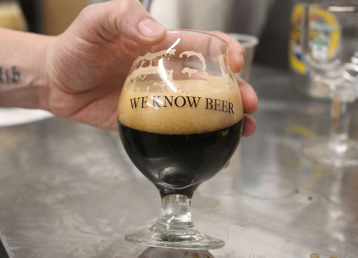 Phil Hottenstein holds up this bourbon stout during a recent meeting with the North Idaho Business Journal. &#147;We know beer&#148; is one of several mottos of Bombastic Brewing, a small-batch production company in Hayden that is helping to propel North Idaho&#146;s craft beer trend.