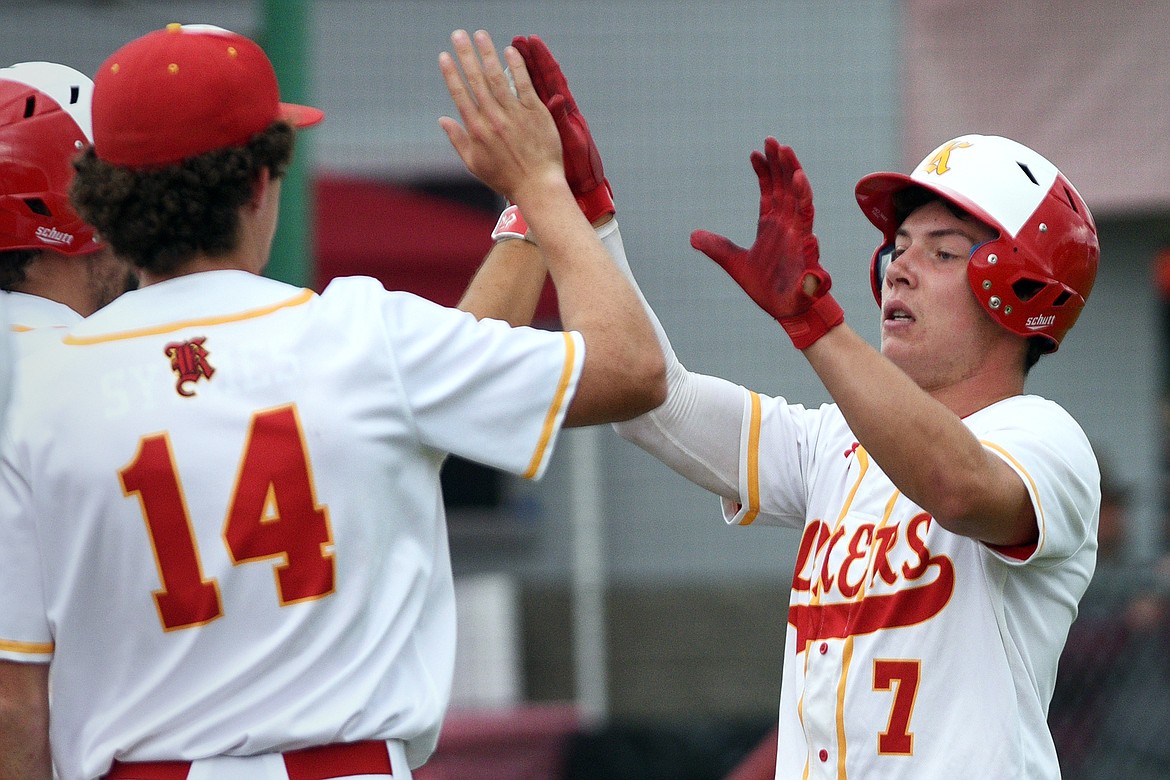 Kalispell Lakers AA&#146;s Randy Stultz high fives with Ryan Symmes (14) and teammates after scoring on a sacrifice fly by Eric Seaman in the bottom of the third against Medicine Hat at Griffin Field on Saturday. (Casey Kreider/Daily Inter Lake)