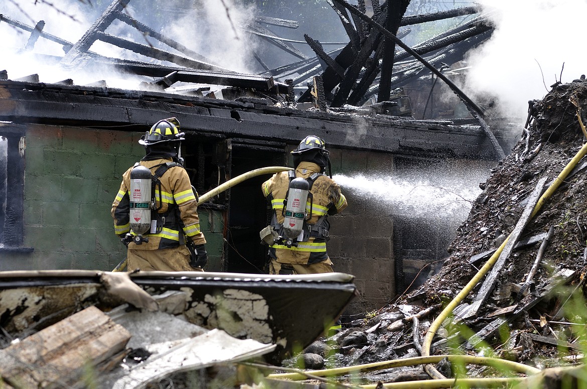 Firefighters continue to spray water on a Ramsay Avenue house that was destroyed by an electrical fire Thursday. The house was in the process of being demolished. (Heidi Desch/Whitefish Pilot)