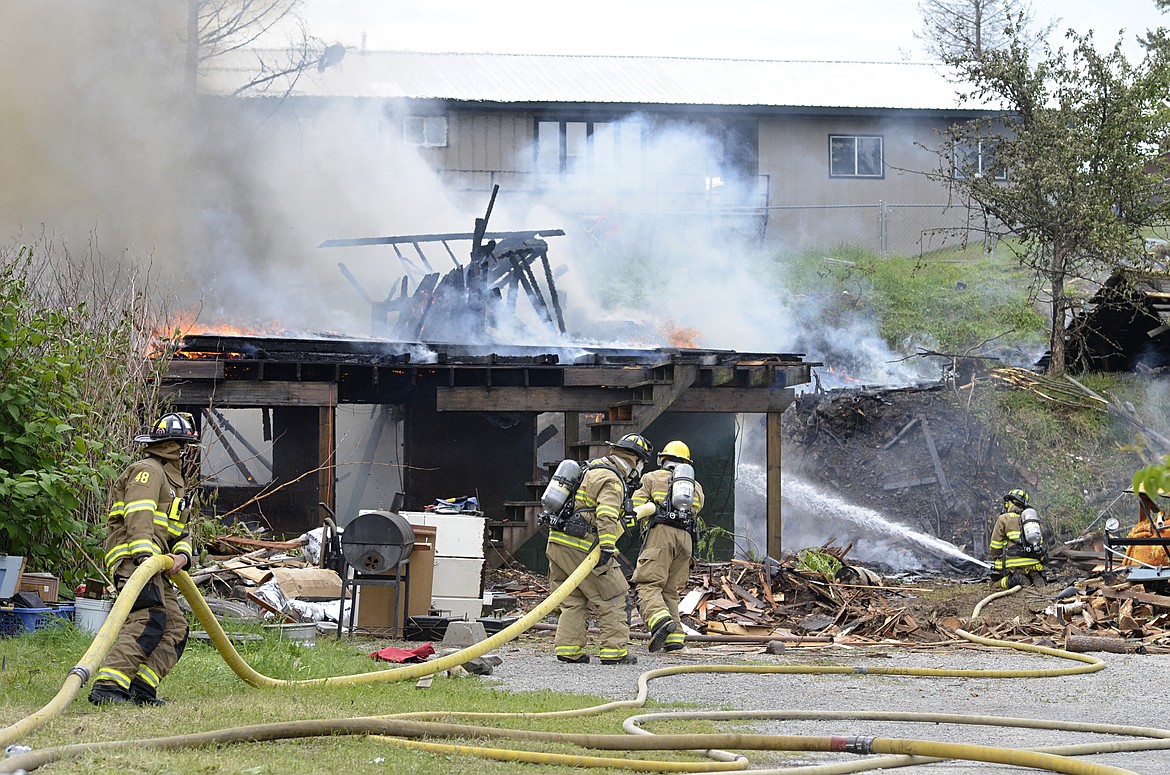 Firefighters continue to spray a flare up at a house that was destroyed by an electrical fire Thursday. The Ramsay Avenue house was in the process of being demolished. (Heidi Desch/Whitefish Pilot)