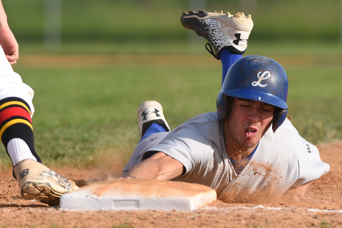 Libby&#146;s Jeff Offenbecher dives back into first base on a pickoff attempt by Lakers AA pitcher Evan Todd. (Casey Kreider/Daily Inter Lake)