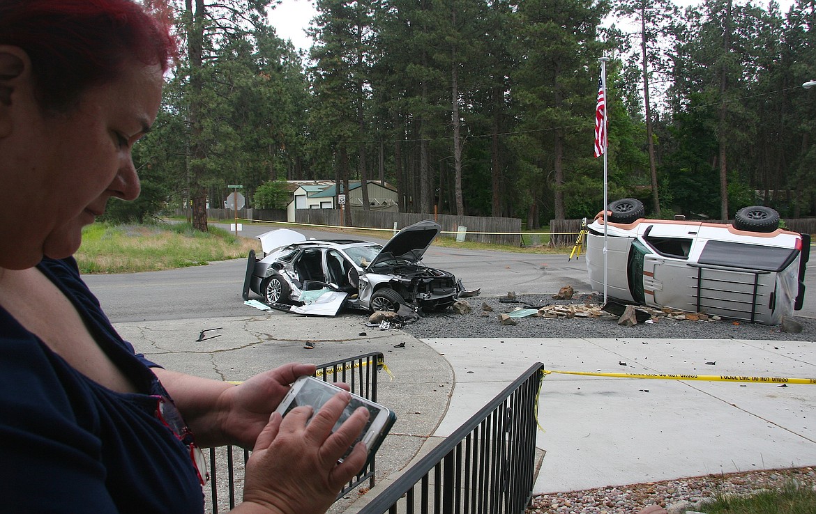 Kimberly Powell reviews her photos of the crash that occurred just outside her front door in Post Falls and injured two on Friday afternoon. Levi Pogue, 26, Spokane, was arrested for aggravated DUI and resisting arrest after the 1999 Chevy Tahoe he was driving crashed into the 2018 Cadillac. (BRIAN WALKER/Press)