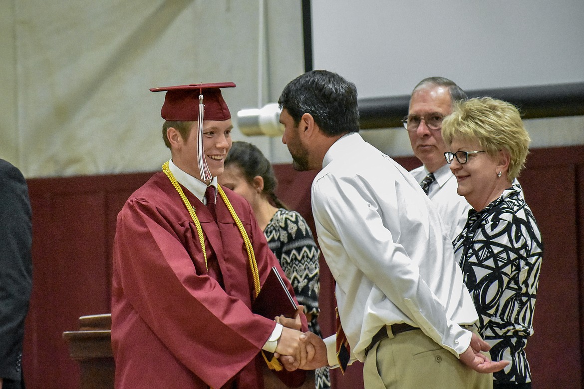 Troy's Royal Johnson is congratulated by honorary speaker and Troy High School teacher Cory Anderson after receiving his diploma at the Troy School Activity Center auditorium for graduation on Saturday, June 2, 2018. (Ben Kibbey/The Western News)