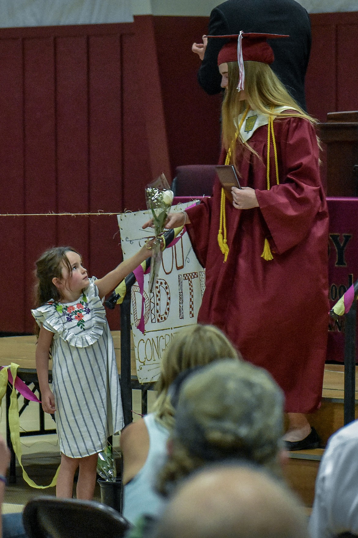 Flower girl Embry Cairns hands a white rose to Troy High School graduate Sarah Osborn as she leaves the stage after receiving his diploma during graduation ceremonies on Saturday, June 2, 2018. (Ben Kibbey/The Western News)