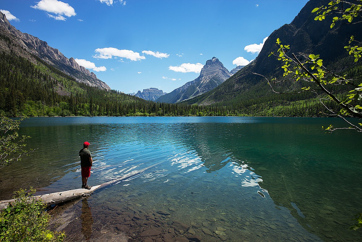 A hiker looks out over Kintla Lake, with Kinnerly Peak rising in the background.