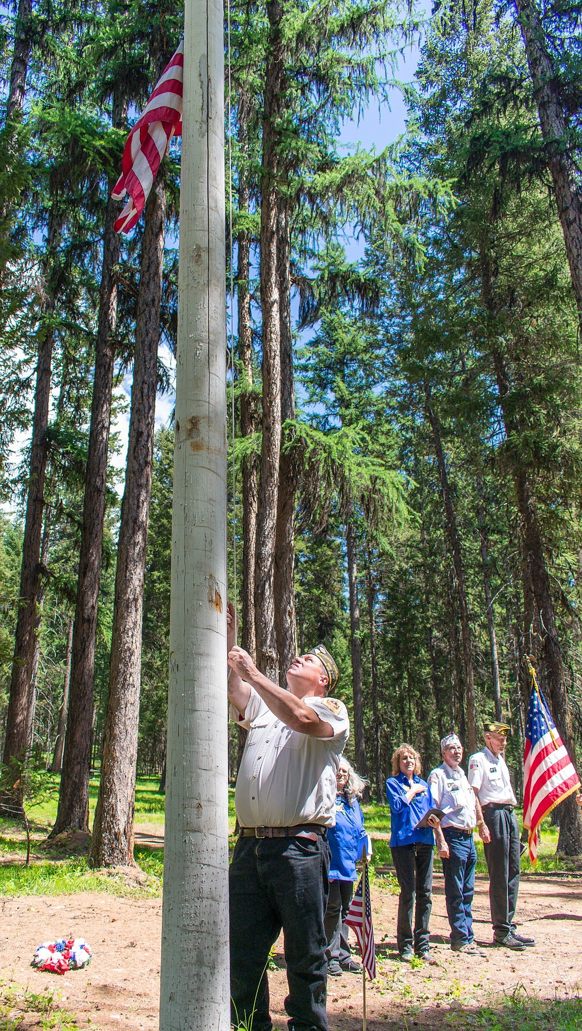 In a Memorial Day ceremony that predates the establishment of Veterans Day, VFW John E. Freeman Post 5514 member Wade Kidder lowers and raises the flag at Boyd Cemetery in the Yaak to honor both deceased and living veterans. (Ben Kibbey/The Western News)