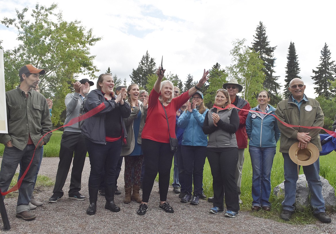 Bakke family friend Donna Hopkins, center, cuts the ribbon Friday officially opening the James R. Bakke Nature Reserve. She is surrounded by folks who assisted in creating the natural park. (Heidi Desch/Whitefish Pilot)