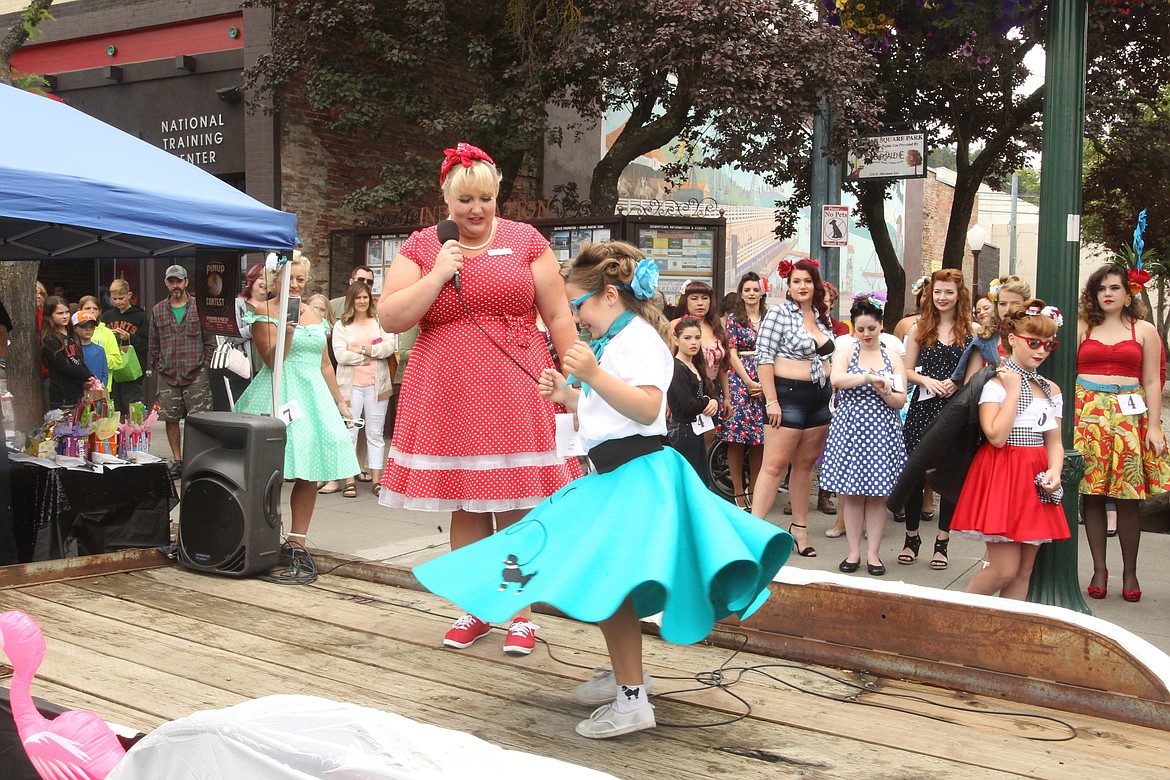 Evalyn Neill, 8, of Hayden, twirls her teal poodle skirt Saturday afternoon during Car d'Lane's debut pin-up contest in front of Sherman Square Park in downtown Coeur d'Alene. The show, presented by the Retro Studio, focused on hair, personality and wardrobe to emphasize the beauty of every gal who competed. (DEVIN WEEKS/Press)
