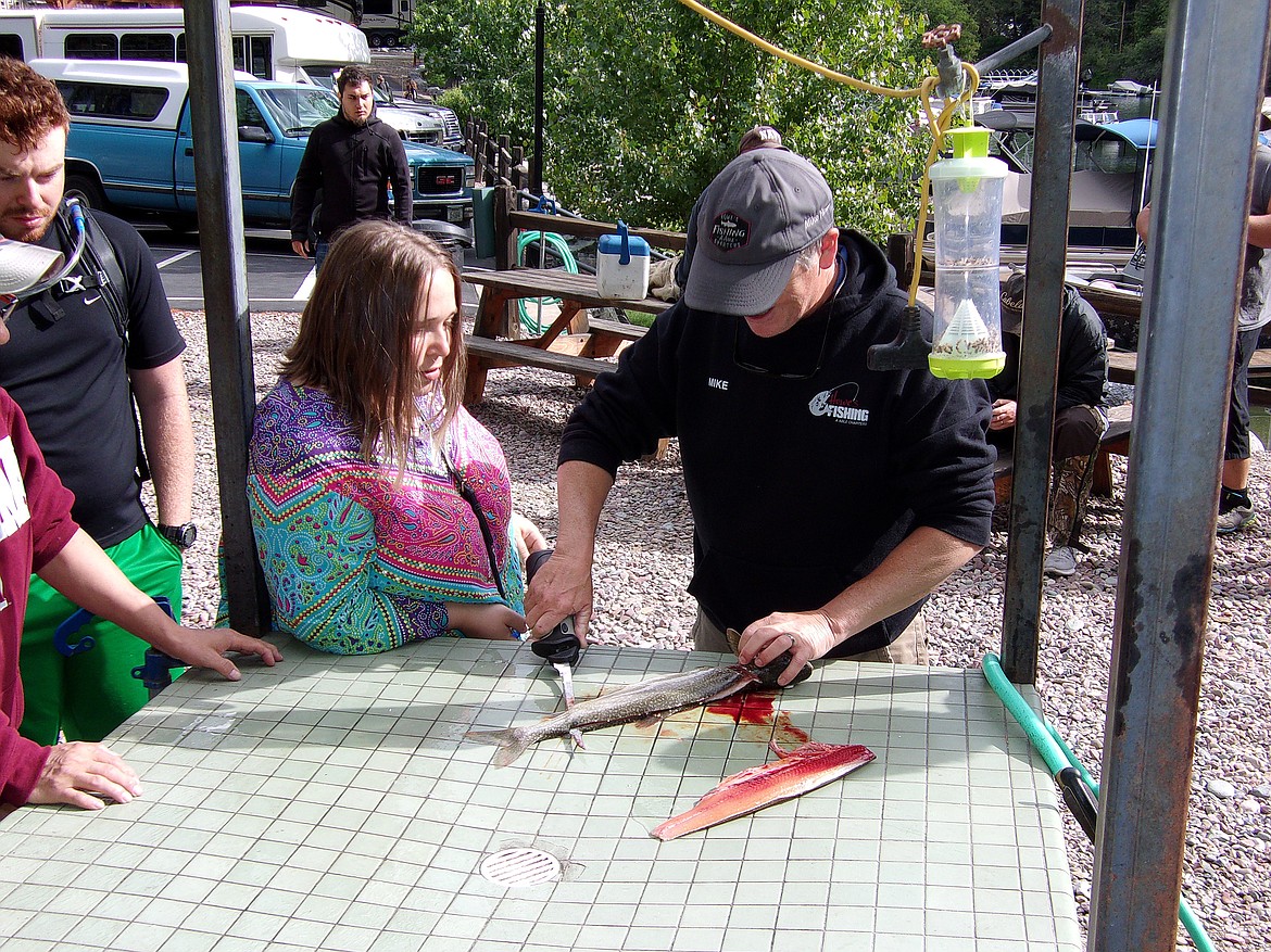 Amey Ginther watches charter boat captain Mike Howe filet a lake trout she caught during Thursday&#146;s 25th annual Jerry Howard Fishing Without Barriers Day on Flathead Lake. (Scott Shindledecker/Daily Inter Lake)