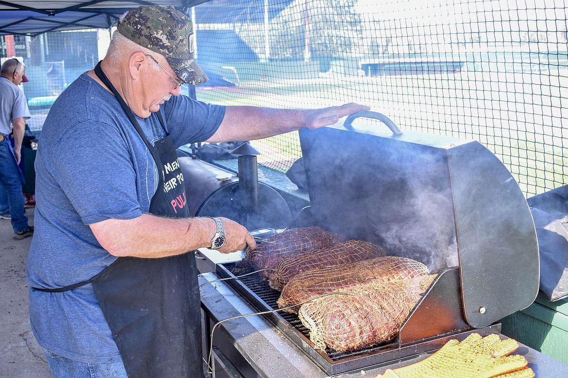 John Morford checks the temperature on some of the prime rib he and Gary Fjelstad donated for the annual Dinner on the Diamond fundraiser at Lee Gehring Field Friday. (Ben Kibbey/The Western News)