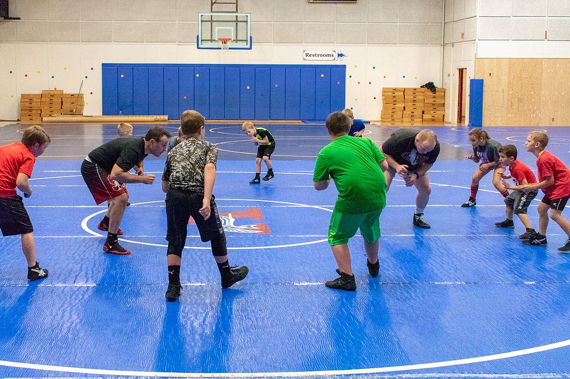 Stanford wrestling Head Coach Jason Borrelli and Eastern Michigan wrestling Head Coach David Bolyard instruct young wrestlers in a proper stance during the second annual Greenchain Wrestling Camp in Libby on Saturday. (Benjamin Kibbey/The Western News)