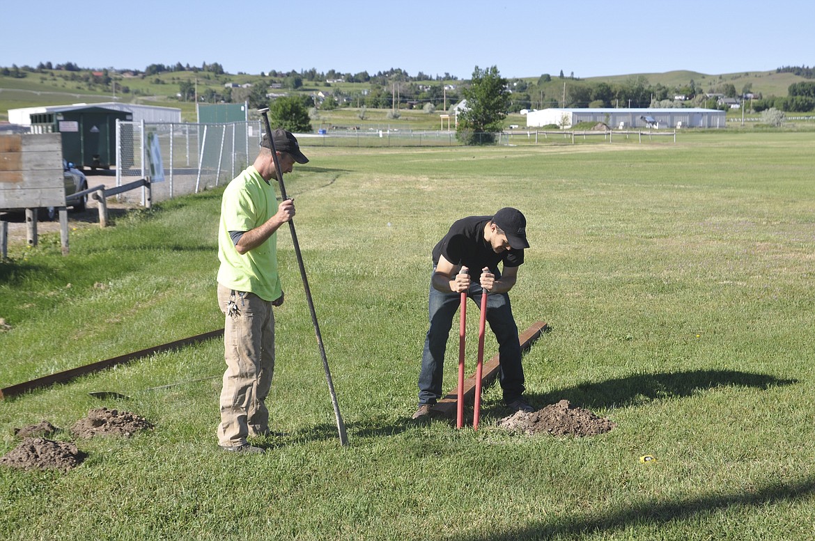 WALTER EGGEBRECHT, left, and Jesse Vargas, of the 7th Avenue Skatepark Association dig holes for posts that will hold a park banner. (Ashley Fox/Lake County Leader)