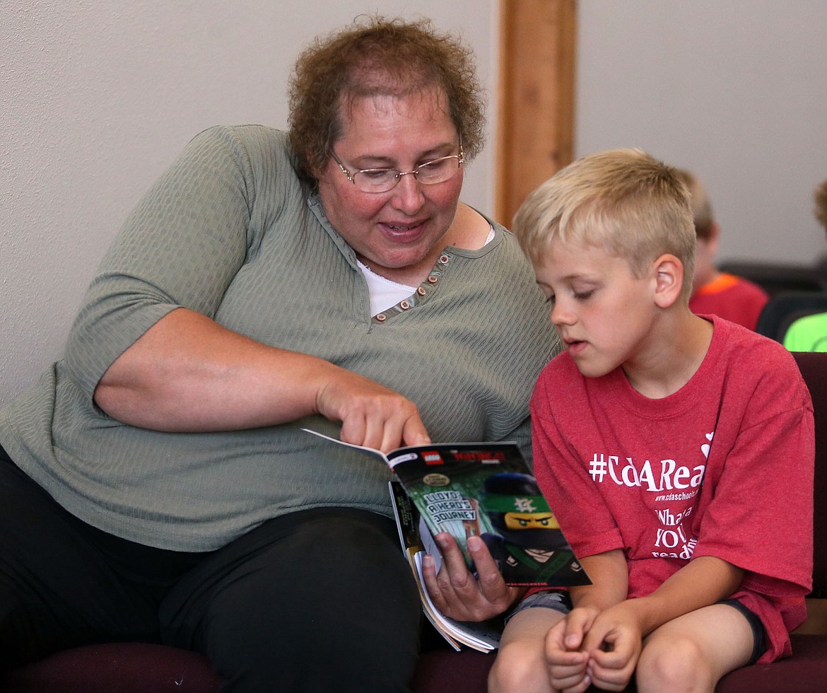 Nanette Braby reads a Ninjago book to her grandson, Ethan Schanuth, on Monday at the Hayden Community Library. The Borah Elementary School second-grader has been to all the CdA Reads events so far this summer, said Braby.