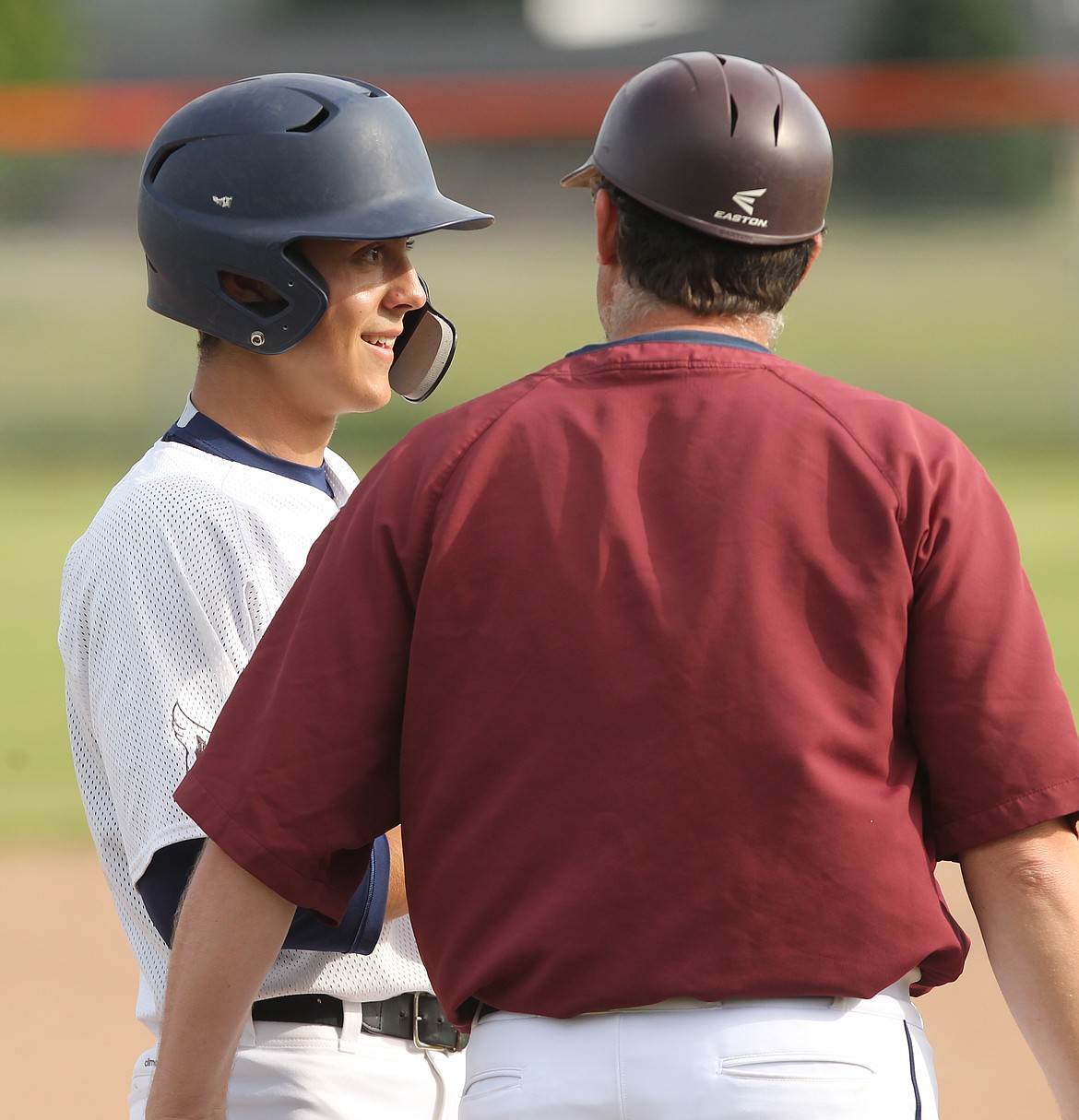 Harrison Reid of Prairie smiles as he chats with coach Pat Call after reaching third base.