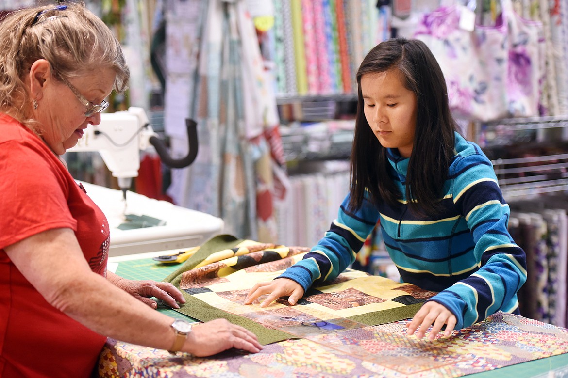 Anna Bergstedt, right, gets some guidance from Betty Prichard during a quilting camp for 12- to 15-year-olds on Thursday morning, June 21, at Glacier Quilts in Kalispell. (Brenda Ahearn/Daily Inter Lake)