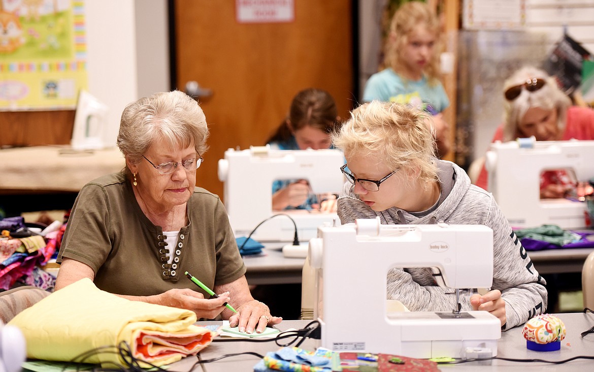 Jane Nelson-Ott helps Isaac Bertrand with his quilting at Glacier Quilts in Kalispell. Bertrand is one of the students taking part in a five-day camp that concluded with students taking home their own completed quilts.