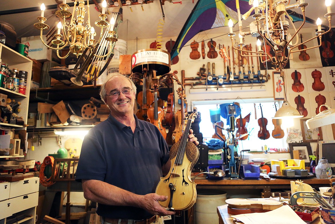 Tom Simensen holds up a violin he spent 19 years working on. The instrument has an eagle carved into the scroll and feather detail down the neck. (Mackenzie Reiss photos/Daily Inter Lake)