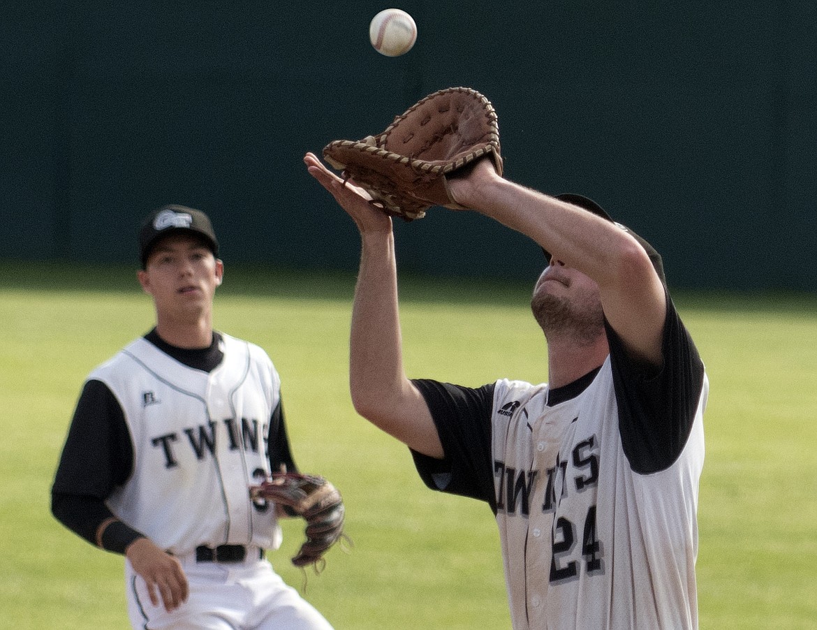 Twins first baseman Dan Seymour catches a fly ball against Yakima Thursday as teammate Tom Hellwig looks on. (Jeremy Weber photo)