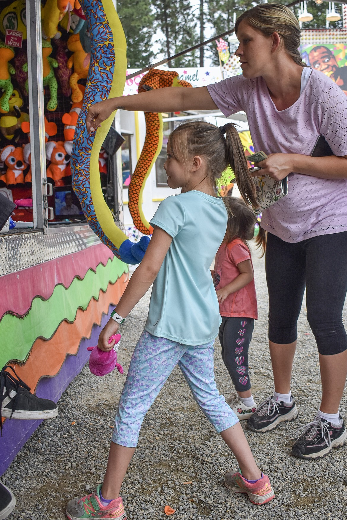 Katie Porteus helps daughter Lexi aim at a carnival balloon at Libby Logger Days on Saturday. 
(Ben Kibbey/The Western News)