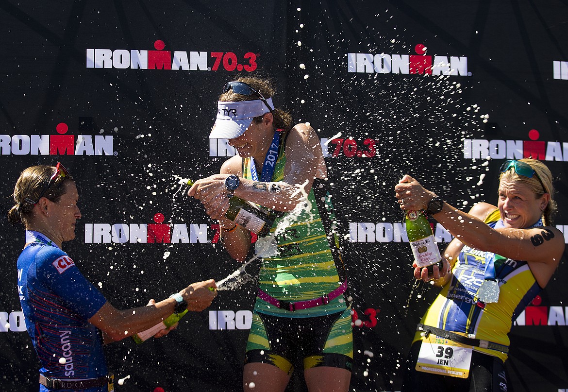 Jen Annett, right, and Linsey Corbin, left, shower first place womens Ironman 70.3 Coeur d'Alene finisher Haley Chura with sparkling cider in 2017. (LOREN BENOIT/Press File)