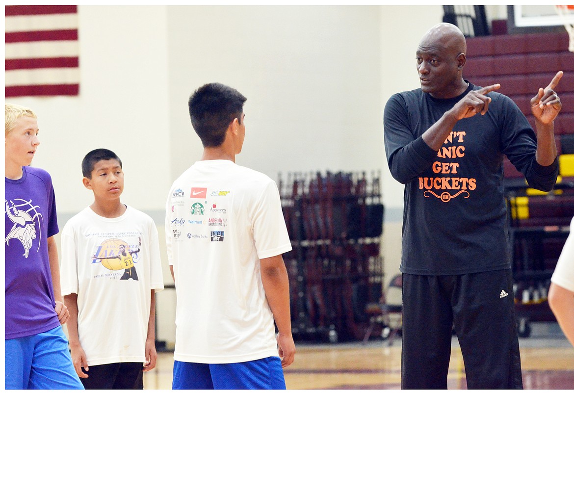 FORMER LOS Angeles Laker Michael Cooper instructs three students of his camp Friday afternoon at Salish Kootenai College. (photo by Jason Blasco/Lake County Leader)