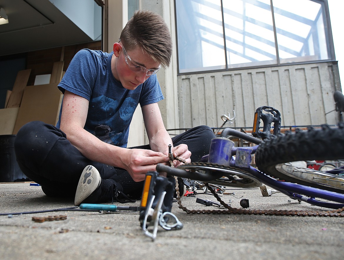 Quinn McGovern puts a chain back together on a tricycle in preparation for the fourth annual GizMotion parade on Saturday, July 7 in City Park. (LOREN BENOIT/Press)