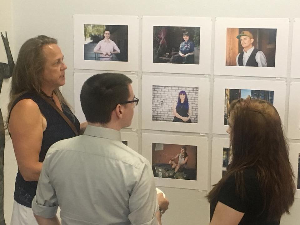 Portraits on display in the &#147;Out - Faces of Pride&#148; art exhibition at Emerge CDA catch the eye of several people during the July 21 opening reception at the Fourth Street gallery. (JULI STRATTON/Courtesy Photo)