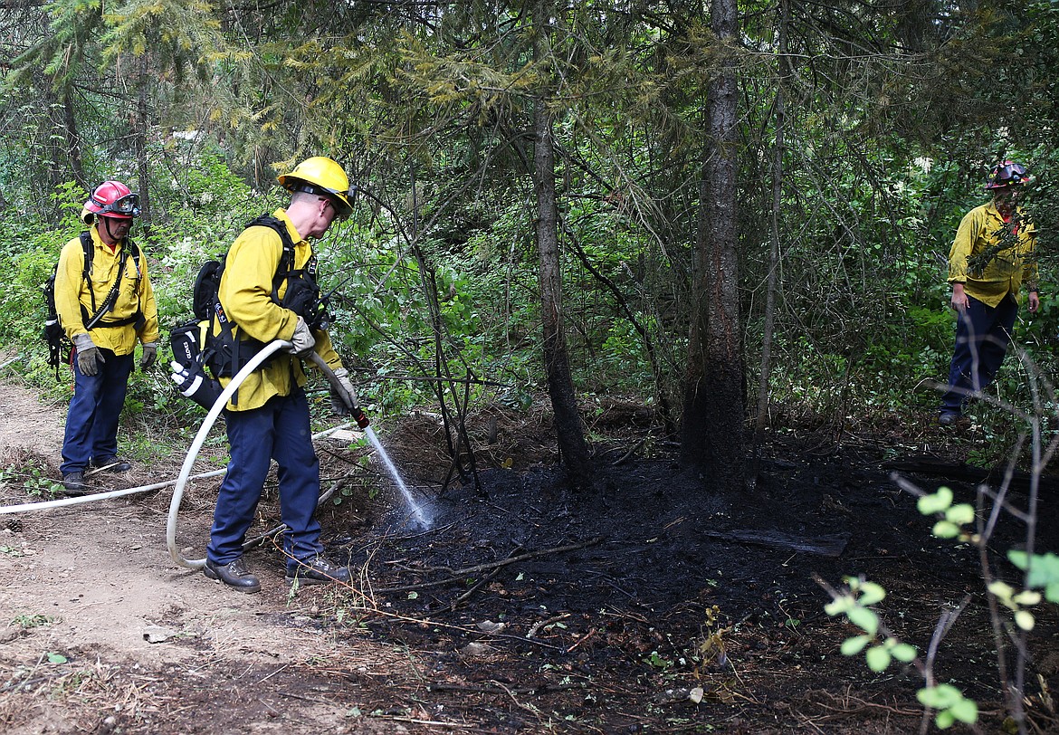 LOREN BENOIT/Press
Matt Smith with the Coeur d&#146;Alene Fire Department sprays down a 20-by-20-foot hot spot early Friday afternoon on Tubbs Hill. The fire is under investigation.